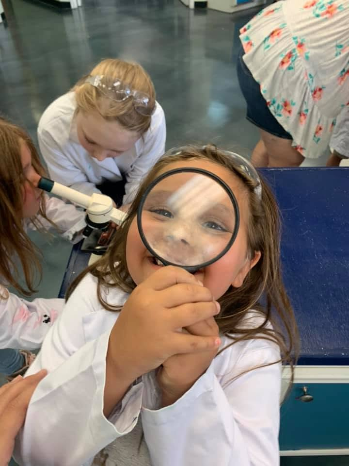 A child looks through a magnifying glass during a hands-on activity