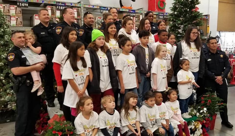 Children and officers gather beside a Christmas tree